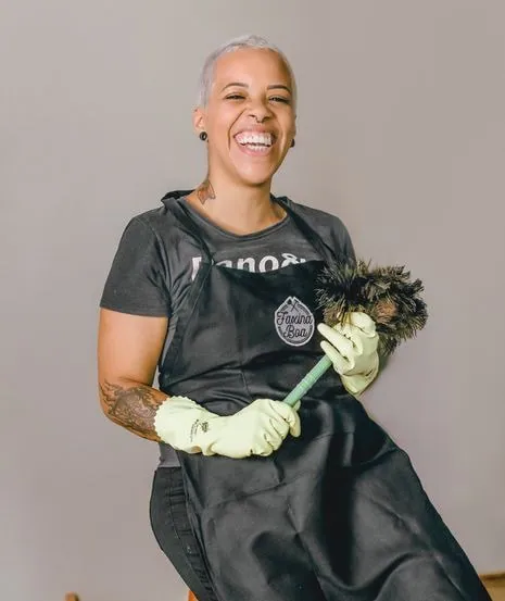 Veronica Oliveira sorrindo com uniforme e utensílios da Faxina Boa